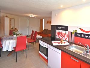 cocina con fregadero y mesa con sillas rojas en Cozy Apartment in Lichtenhain Germany With Garden en Lichtenhain