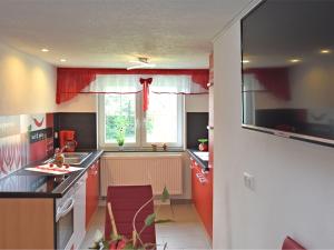 una cocina con cortinas rojas y una ventana en Cozy Apartment in Lichtenhain Germany With Garden en Lichtenhain