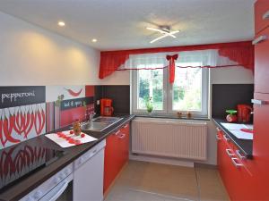 cocina con armarios rojos, fregadero y ventana en Cozy Apartment in Lichtenhain Germany With Garden en Lichtenhain