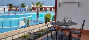a table and chairs next to a swimming pool at Sun Beach 14 Espino Castillo in Caleta De Fuste