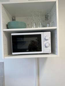 un forno a microonde bianco in un armadietto bianco della cucina di Chambre proche de paris métro 7 La Courneuve 3 a La Courneuve