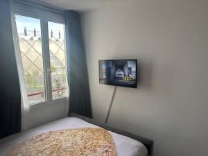 a bedroom with a tv on the wall next to a window at Chambre proche de paris métro 7 La Courneuve 3 in La Courneuve