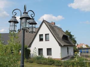 a white house with a roof and a street light at Cosy Apartment in Pepelow near Baltic Sea in Pepelow
