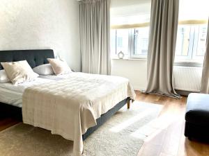 Un dormitorio con una cama con sábanas blancas y ventanas. en Royal Attic Luxury Gdansk Old Town, en Gdansk