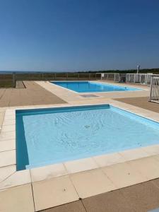 - une grande piscine bleue revêtue de carrelage dans l'établissement Appartement d'une chambre a Guidel a 100 m de la plage avec vue sur la mer piscine partagee et balcon amenage, à Guidel