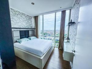 um quarto com uma cama e uma grande janela em Exquisite 3BR Surabaya Apartment at Via Tower Ciputra World by Le Ciel Hospitality em Surabaya