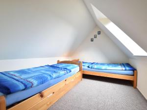 2 Betten in einem Dachzimmer mit blauer Bettwäsche in der Unterkunft Modern Apartment in Elmenhorst near Sea in Elmenhorst