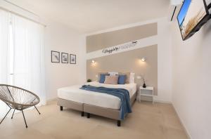 a white bedroom with a bed and a chair at Sve Suites Cagliari in Cagliari