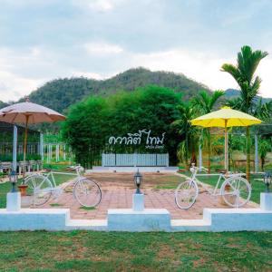 dos bicicletas estacionadas bajo sombrillas en un parque en Quality Time Farmstay: YardHouse#5, en Ban Pa Lau