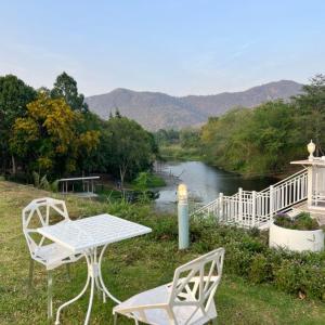 a table and two chairs sitting next to a river at Quality Time Farmstay: YardHouse#5 in Ban Pa Lau