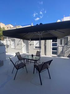 einen Tisch und Stühle unter einem Sonnenschirm auf einer Terrasse in der Unterkunft Alexandra apartment in Athen