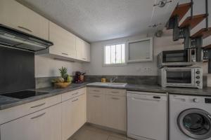 eine Küche mit weißen Schränken, einer Spüle und einer Mikrowelle in der Unterkunft La Barque in Le Barcarès