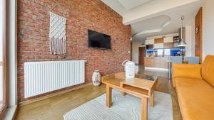 a living room with a brick wall and a table at Apartamenty Sun & Snow Melioracyjna in Karwia