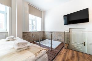 a bathroom with a tub and a bed and a tv at Design Apartments Lužánky in Brno