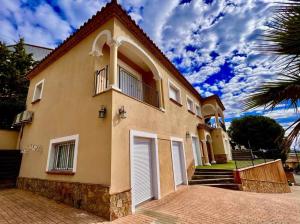 a house with white doors and a palm tree at Casa Mas Ambros con piscina desbordante in Calonge