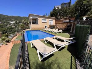 a swimming pool with lounge chairs and a house at Casa Mas Ambros con piscina desbordante in Calonge