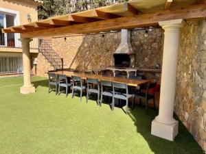 a wooden table and chairs under a wooden pergola at Casa Mas Ambros con piscina desbordante in Calonge