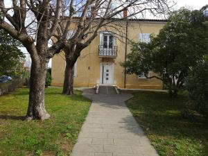 una casa amarilla con una puerta blanca y árboles en Depandansa Vista Parco, Izola, en Izola