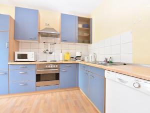 a kitchen with blue cabinets and a microwave at Cozy Apartment in Rerik near the beach in Rerik