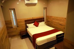 GRANDE IVORY INN في كالباتّا: غرفة نوم بسرير ومخدة حمراء
