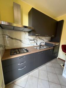 a kitchen with black cabinets and a stove and sink at Casa Oasi Sette Laghi in Mercallo