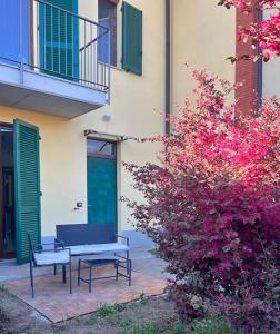 two benches sitting next to a building with pink flowers at Casa Oasi Sette Laghi in Mercallo