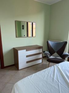 a bedroom with a dresser and a chair and a mirror at Casa Oasi Sette Laghi in Mercallo