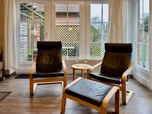 due sedie e un tavolo in una stanza con finestre di Inselsonne (9093) - [#12519] a Wulfen auf Fehmarn