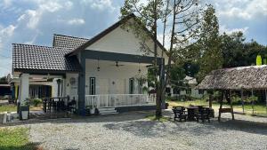 a small white house with a table and chairs at D'LaMar Homestay in Pendang