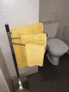 a towel rack with yellow towels next to a toilet at Recantos do Castanheiro in Porto Moniz