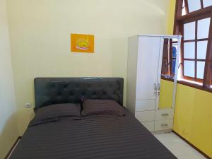 Bebek Kuning Residence في Blimbing: غرفة نوم مع سرير وخزانة