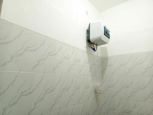 a white tiled bathroom with a soap dispenser on the wall at Bebek Kuning Residence in Blimbing