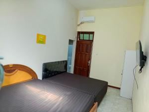 a bedroom with a bed and a television in it at Bebek Kuning Residence in Blimbing