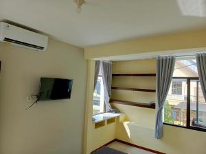 a living room with a tv and a window at Bebek Kuning Residence in Blimbing