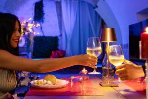 Twee mensen houden wijnglazen aan tafel. bij Apulia Suite in Castellana Grotte