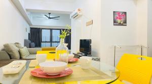 een woonkamer met een glazen tafel en gele stoelen bij Sri Murni Homestay Aurora Place Bukit Jalil in Kuala Lumpur