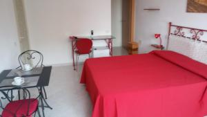 a bedroom with a red bed and a table and chairs at Ca'Mea in Villasimius
