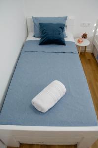 a white bed with a blue bedspread and a pillow on it at Kuća za odmor 'Luca' in Ljubuški