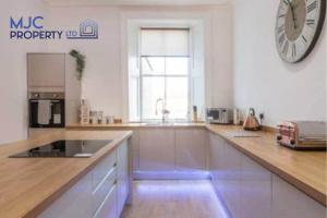 a large white kitchen with a large clock on the wall at The Old Bank in Hawick