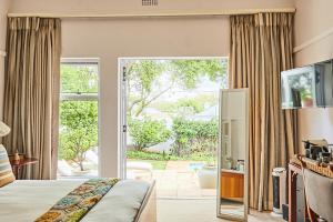 a hotel room with a bed and a sliding glass door at Maison Jacaranda in Johannesburg