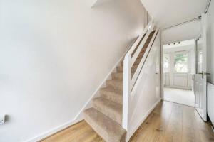 una escalera en una casa con paredes blancas y suelo de madera en A Luxurious 3 Bed-Terrance House en Londres