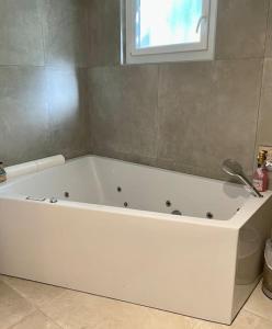 La salle de bains est pourvue d'une baignoire blanche et d'une fenêtre. dans l'établissement Villa avec piscine au cœur de la ville, à Tournon-sur-Rhône