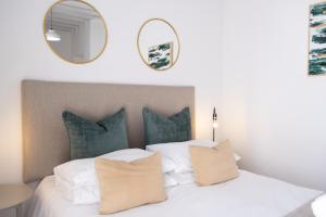 una camera da letto con letto bianco, cuscini e specchio di George Lodge International a George