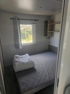 a small bedroom with a bed and a window at Charmant mobil-home premium 304 in Narbonne