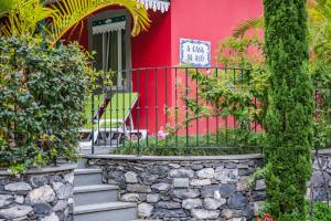 een rood huis met een bord ervoor bij Quinta da Tia Briosa by Madeira Sun Travel in Ponta do Sol