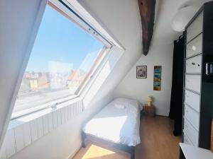 una piccola camera con un letto e una grande finestra di So British ! Appart atypique et sa petite terrasse a Poitiers