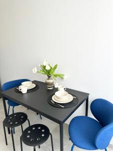 a black table with blue chairs and a vase with flowers at Modernūs apartamentai Šilutėje in Šilutė