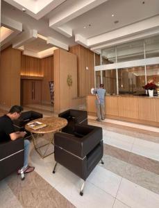 un uomo in piedi in una hall con tavolo e sedie di Fully Furnished 2BR exclusive pool view apartment in Medan a Medan
