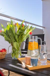 a table with a vase of flowers and a pitcher of orange juice at Lomená Apartments - Free Garage in Košice