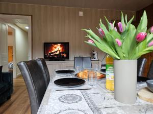 a dining room table with a vase of flowers and a fireplace at Appartement Chaleureux Gérardmer proche forêt in Gérardmer